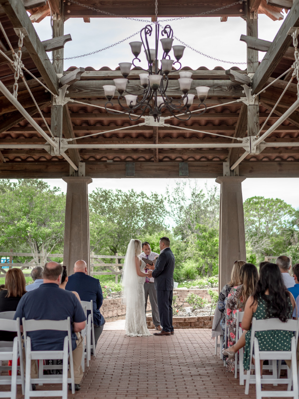 Everlasting Elopements couple standing in front of guests during ceremony under a beautiful chandelier at South Texas Botanical Garden