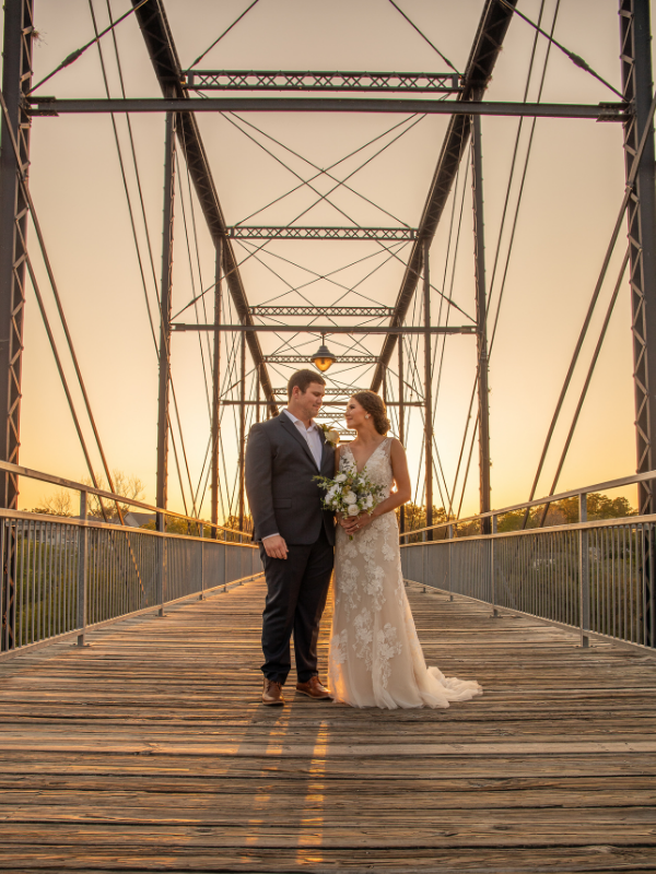 Everlasting Elopements couple looking at each other on a bridge with the sunset behind them at Faust Street Bridge