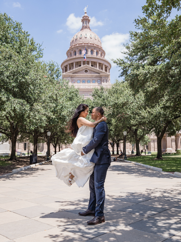 Everlasting Elopements couple holding each other near trees in front of the state building at Texas State Capitol