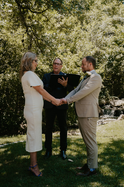 Everlasting Elopements couple holding hands in front of their officiant during their ceremony. 