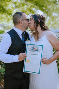 Everlasting Elopements couple kissing and holding up their signed marriage license on the San Antonio Riverwalk