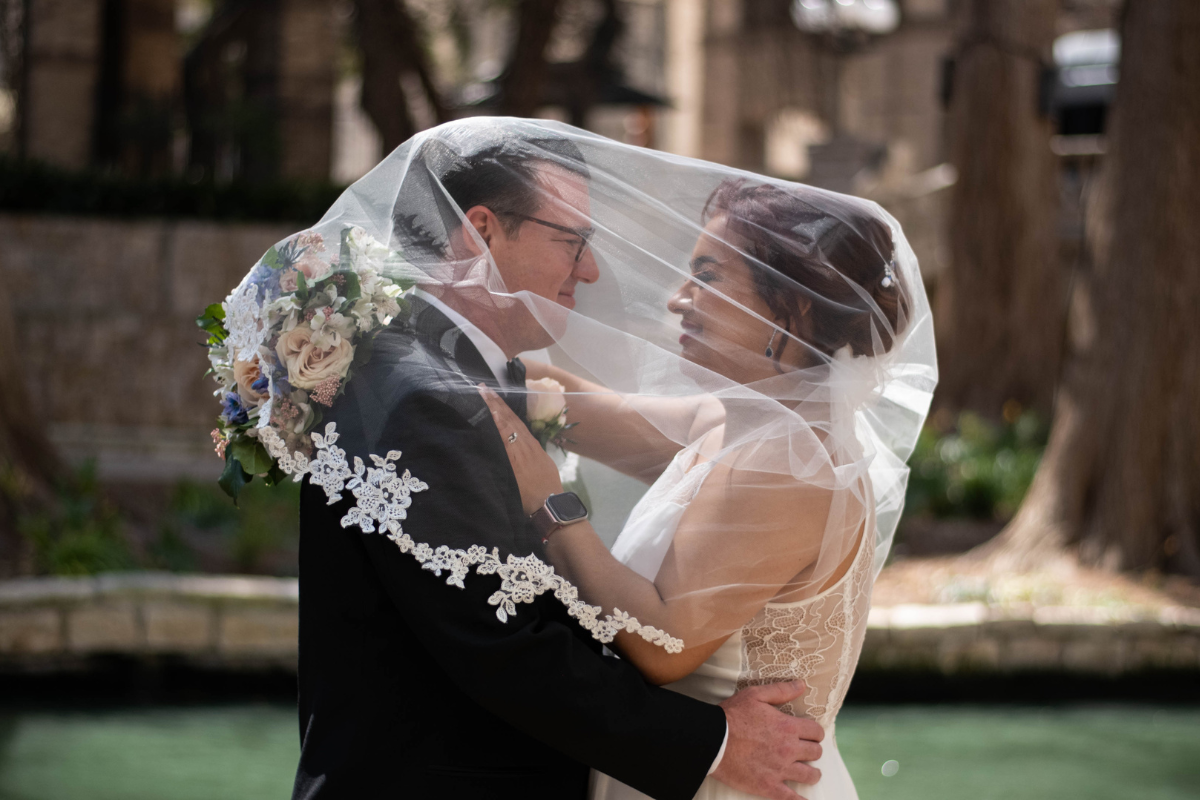 Everlasting Elopements couple staring into each others eyes and smiling under the brides veil in front of the San Antonio Riverwalk